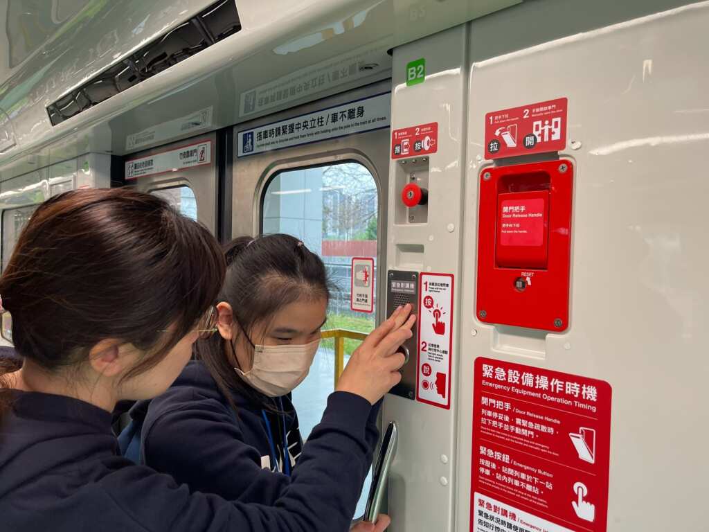 視障學生們以觸摸方式認識捷運車廂內緊急對講機。