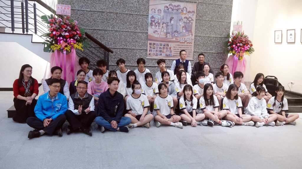 ▲明倫國中第26屆美術班27位畢業生，於3月4日至23日在員林演藝廳舉辦「藝類」畢業美展，今日舉行開幕式，師生及與會貴賓一同席地而坐合唱。（記者林明佑攝）