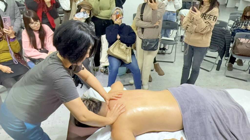 ▲長原老師詳細示範如何透過按摩肩膀、背部與顱部,改善關節僵硬、耳鳴、駝背等問題,讓在場學生驚嘆不已。(記者林明佑翻攝)