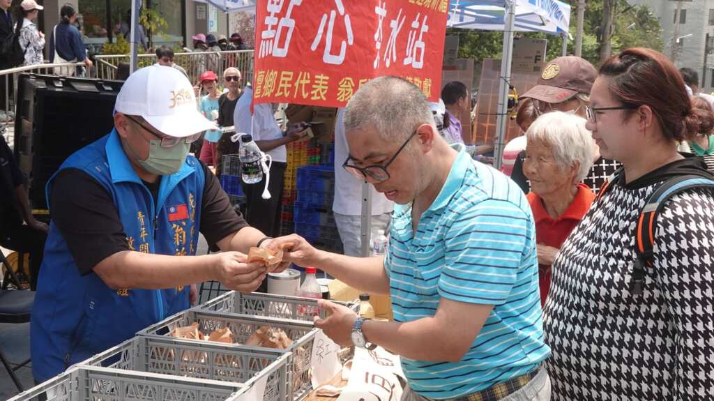 ▲花壇鄉民代表翁啟祐發送現烤紅豆餅給香燈腳補充體力。(記者林明佑攝)