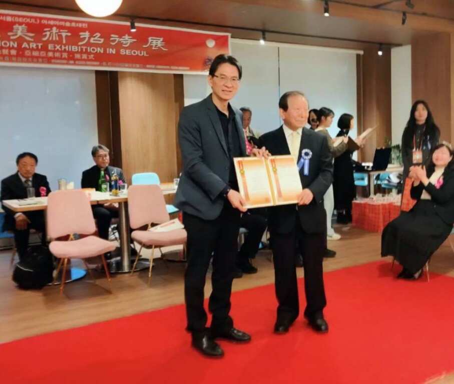 ▲韓國文化藝術研究會會長姜信雄於韓國首爾亞細亞藝術展開開幕式現場頒贈「特別貢獻狀」給林家同總院長。(記者林明佑翻攝)