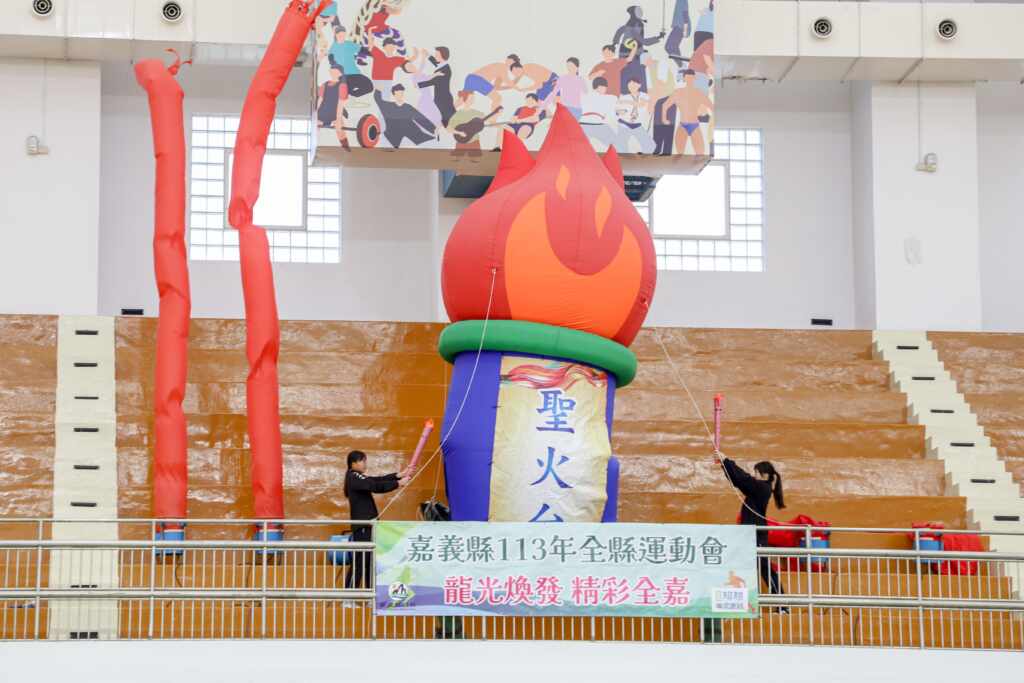 ▲梅山國中王彤綺選手與太保國中林芳琪選手分持火炬進場,登上聖火台點燃聖火,為113全縣運動會揭開序幕。(嘉義縣政府提供)