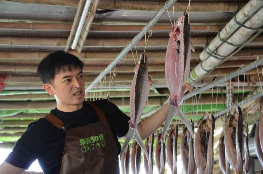 ▲凍齡男神田家達換上青蛙裝,跟著東石50分life工作室執行長江柏儒到魚塭圍網抓虱目魚。(嘉義縣政府提供)