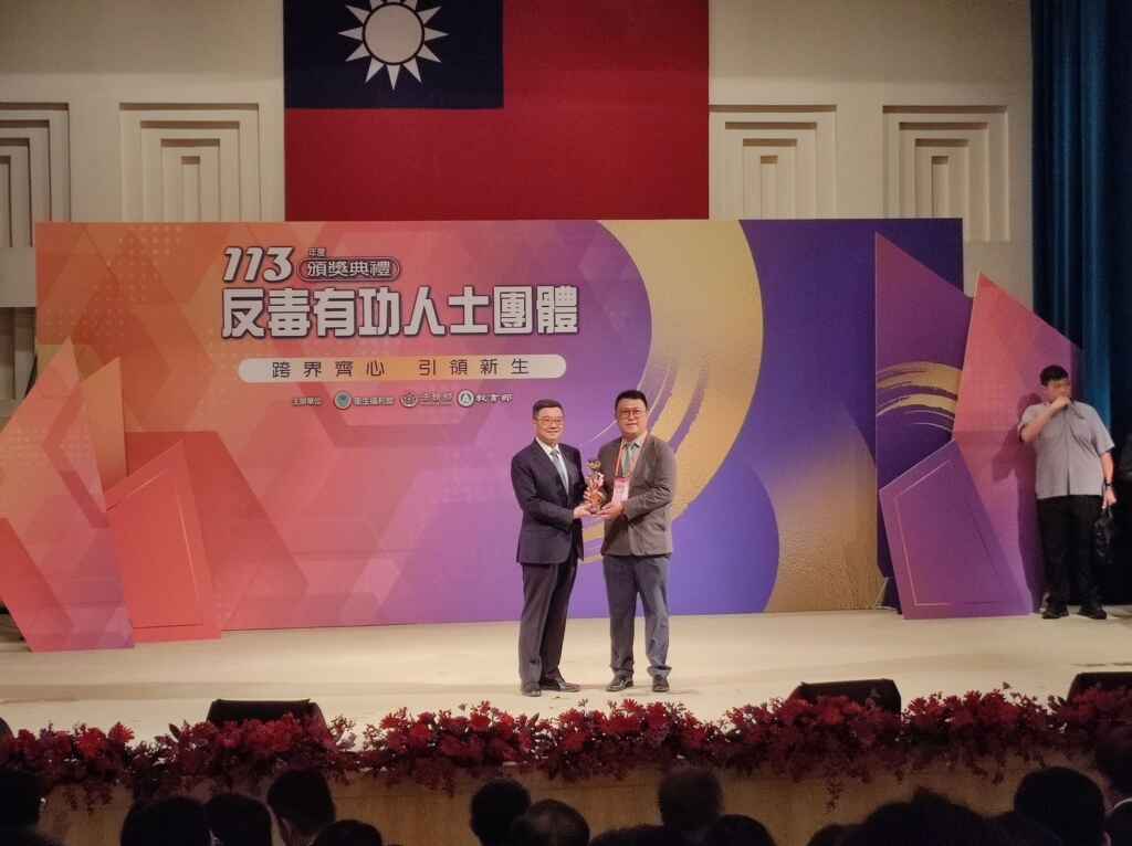 ▲許哲維從行政院長卓榮泰手中領取反毒有功人士獎盃。(中彰投分署提供)