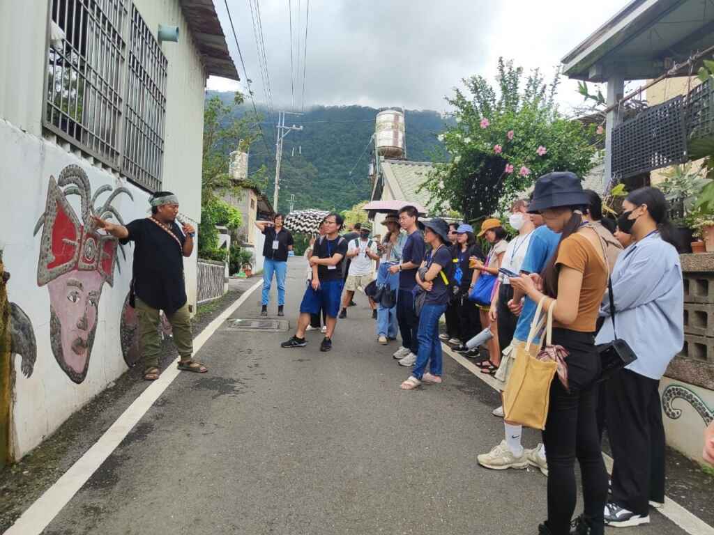 ▲進駐於屏東智慧農業學校的夥伴、青葉部落社區發展協會理事長巴俊傑帶領青年走讀部落,街道上處處可見魯凱族神話故事的藝術牆,彷彿置身戶外美術館。(屏東縣政府提供)